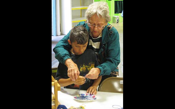 Getting the job done together, as this volunteer helps a child with his artwork. Santa Clara County Fair, San Jose