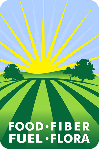 License plate badge illustratrion of a yellow sunrise over a hillside with green rows of crops. Text overlay: FOOD - FIBER - FUEL - FLORA