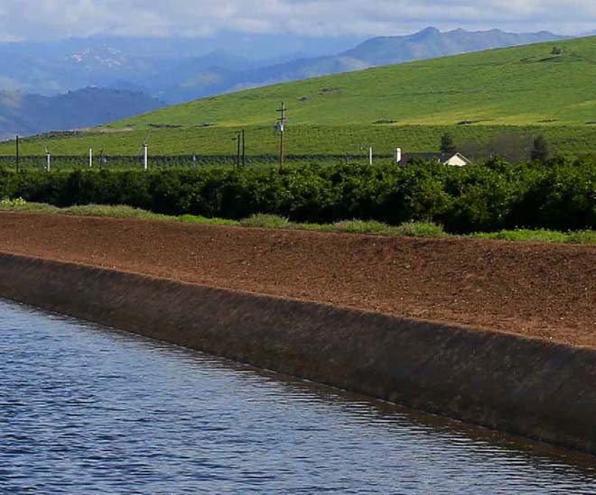 An irrigation pong near a farm beside rolling hills